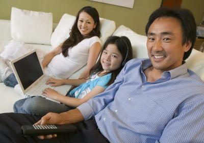 Une famille regarde la télévision et utiliser un ordinateur portable dans le salon ensemble