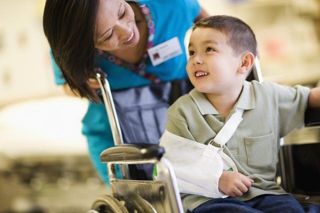 Un garçon est transporté dans un fauteuil roulant par un médecin.