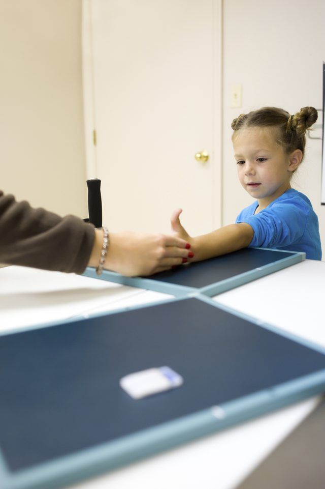 Un médecin place une fille's arm on an xray pad.