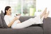 Une femme enceinte sur le canapé manger des céréales.