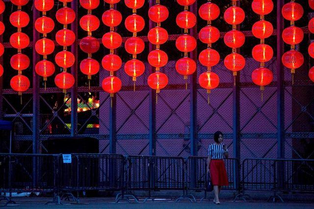 Une femme passe par plusieurs lanternes rouges suspendues.