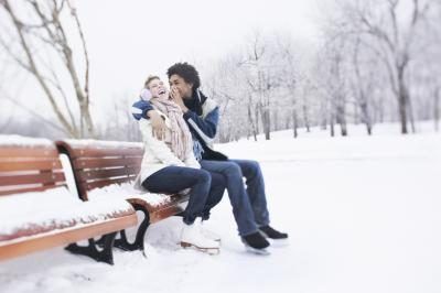 Un couple est assis sur un banc de parc porter des patins à glace.