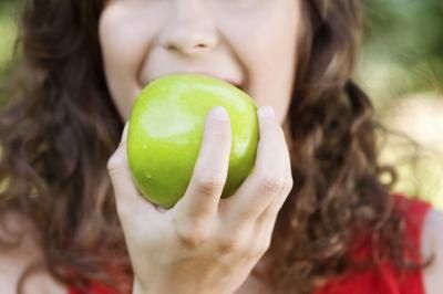 Femme sur le point de mordre une pomme verte.