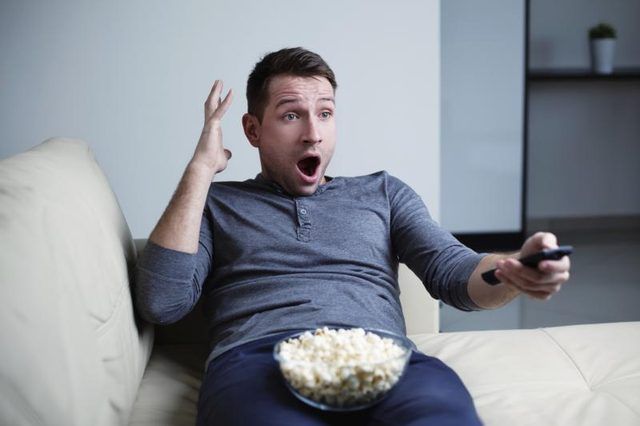 Homme surpised regarder un film avec pop-corn.