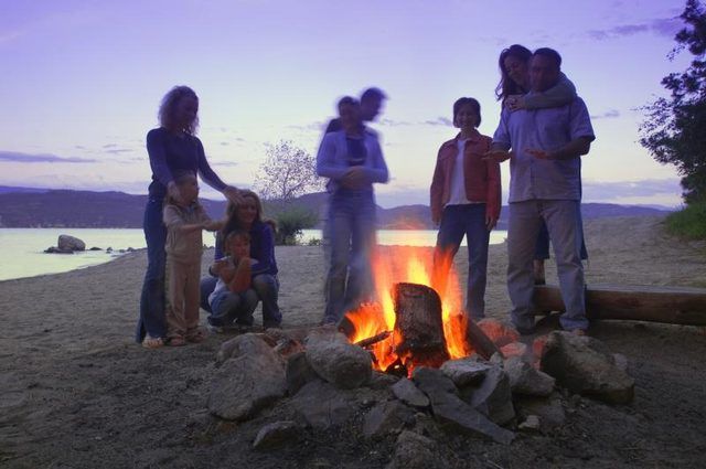 Une famille à un feu près de l'eau.