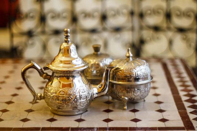 Un thé marocain métallique fixé sur un dessus de table de tuiles.