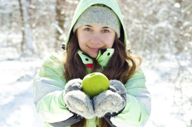 Femme tenant la pomme congelé dans des températures glaciales à l'extérieur.