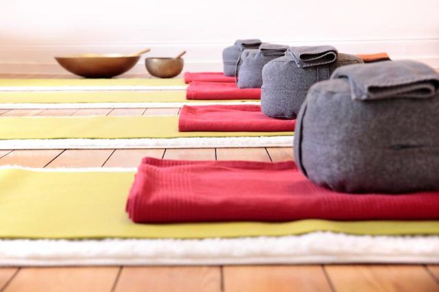 Une rangée de tapis de yoga et oreillers dans un studio
