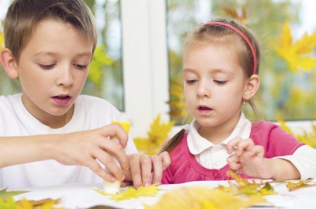 Un jeune garçon et une fille faire de l'artisanat à partir de feuilles d'automne.