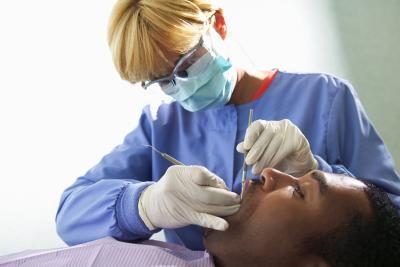 Une hygiéniste dentaire nettoie dents d'un patient.