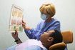 Une assistante dentaire carte d'une femme de la santé des gencives en revue avec un patient de sexe masculin.