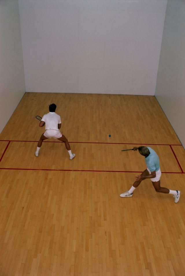 Deux hommes jouent au racquetball à un tribunal dans le gymnase.