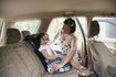 mère aidant sa fille dans un siège d'appoint de voiture