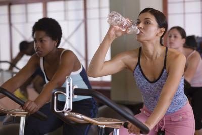 Une femme boit une bouteille d'eau pendant l'exercice à la salle de gym.