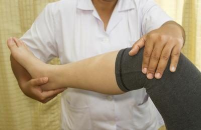 Un travailleur de la santé examine une femme's leg.