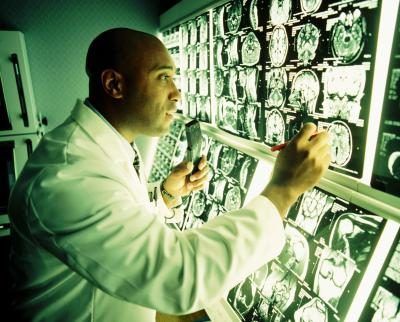 Docteur regardant par-dessus écrans de contrôle IRM