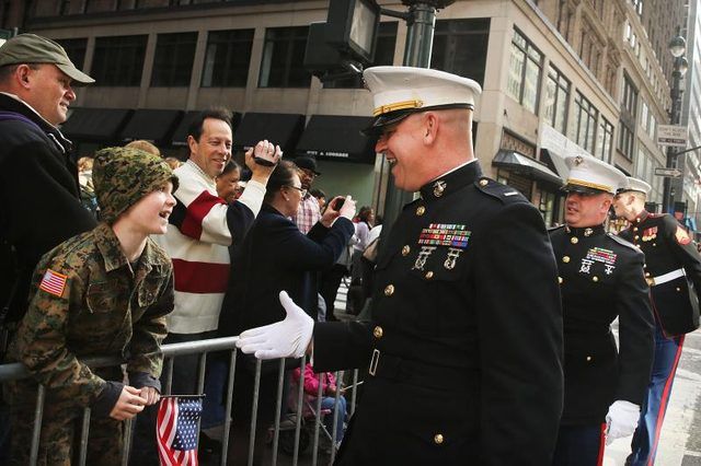 Un soldat du Corps des Marines sur le point de serrer la main avec un garçon lors d'un défilé.