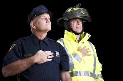 Deux pompiers tiennent leurs mains sur leurs cœurs tout en chantant l'hymne national américain