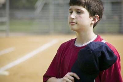 Un jeune garçon tient sa casquette de baseball sur son cœur en chantant l'hymne