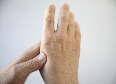 Une femme âgée expieriences douleur de l'arthrite dans sa main.