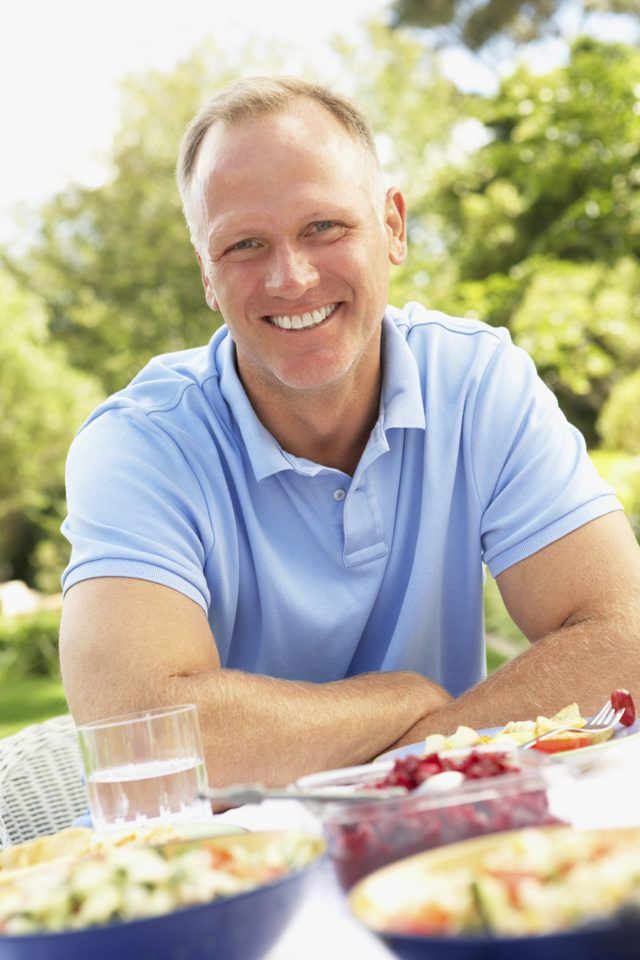 Un homme est assis à une table en plein air à un repas-partage.