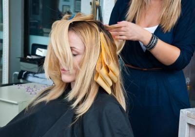 Jeune femme ayant ses cheveux de couleur à un salon de coiffure
