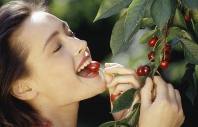 Jeune femme cueillant des cerises d'arbre.