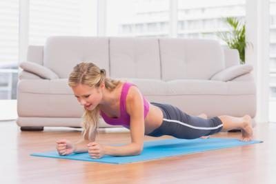 Jeune femme faisant la position de planche sur un tapis de yoga.