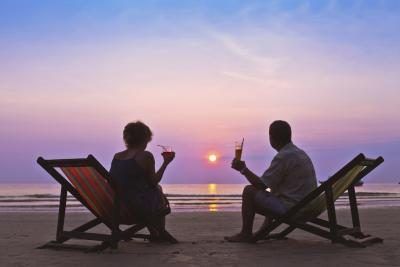 Couple assis ensemble sur la plage au coucher du soleil.