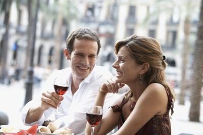 Un couple est de boire du vin à un café en plein air.