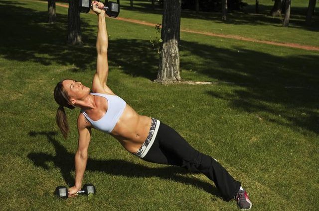 Femme faisant des planches latérales avec des poids dans un parc en plein air.