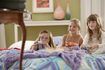 Trois filles jouant à un jeu vidéo dans le lit tout en grignotant du pop-corn.