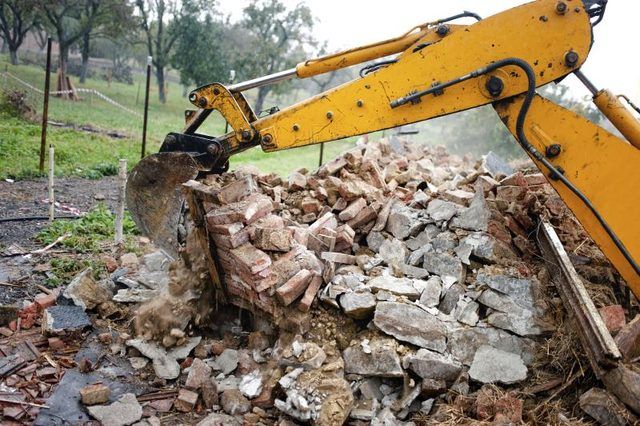 Une excavatrice enlève les débris d'un chantier de démolition.