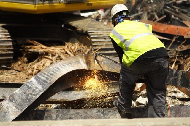 Un travailleur coupe une poutre d'acier sur un chantier de démolition.