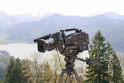 Une caméra est installée sur un trépied dans un décor naturel.