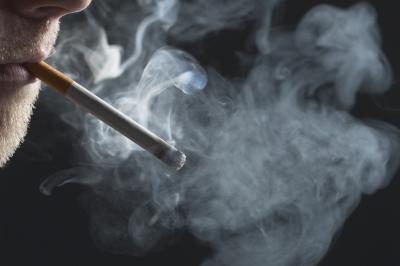 Un homme fume une cigarette, fumer peut conduire à la déglutition d'air.