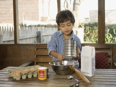 Un jeune garçon se prépare à tamiser la farine dans un grand bol de cuisson