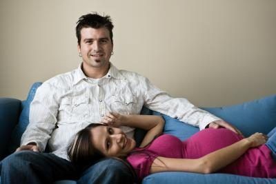 femme enceinte couchée sur le canapé avec son mari