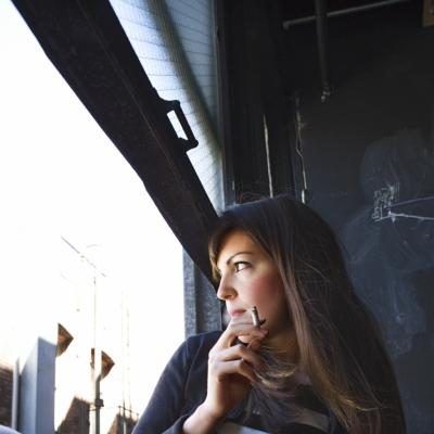 Jeune femme de fumer par la fenêtre ouverte