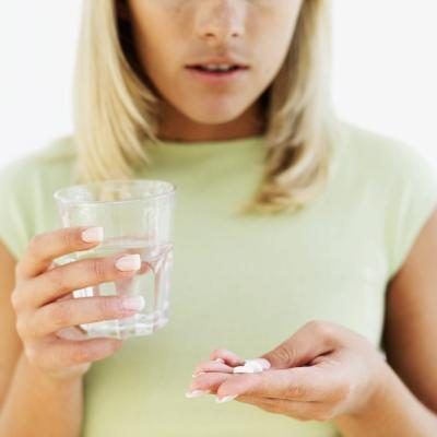 Gros plan d'une femme avec des pilules et un verre d'eau.